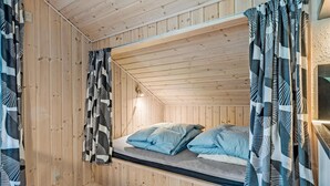 A wooden cabin room with a bunk bed, patterned curtains, and a small window. - Cozy home in Fårvang with WiFi (Fårvang)