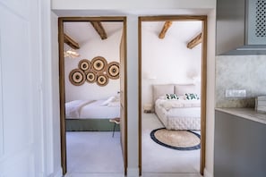 Una habitación con una cama, un taburete pequeño, un tapete redondo y una pared decorada con adornos circulares tejidos.