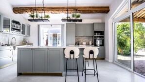 Een moderne keuken met grijze kastjes, een marmeren aanrechtblad en een groot keukenblok met barstoelen.