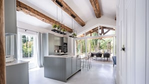 Een moderne keuken met een centraal eiland, houten balken en grote ramen.