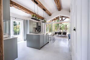 A modern kitchen with a central island, wooden beams, and large windows.