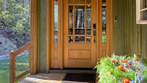 Une porte d’entrée en bois avec des panneaux de verre, un porche en bois et un paillasson.