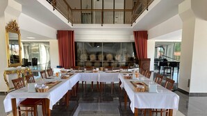 A large dining area with multiple tables set for a meal, a grand mirror, and a view of the kitchen through glass doors. - Etruscan Boutique Hotel (Eceabat)