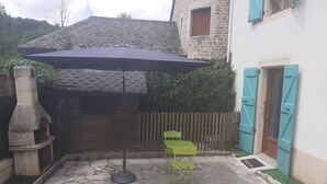 A stone patio with a table and chairs, a stone oven, and a wooden fence.