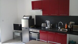 A compact kitchen with red cabinets, a toaster, a coffee maker, and a sink.