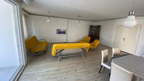 Une pièce comprenant un lit, deux chaises jaunes, une table et un meuble.