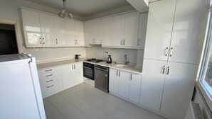 Une cuisine moderne avec des meubles blancs, une cuisinière à gaz et un lave-vaisselle.