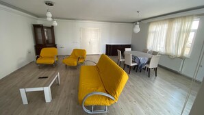 Un salon comprenant un canapé, des fauteuils, une table à manger et une cheminée.