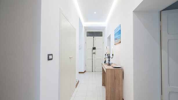 A hallway with white walls, a wooden bench, and a door at the end. - Exclusive  apartment in Perugia centre with parking  (perugia)