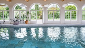A swimming pool with arched windows and a wooden ceiling.