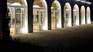 A building with a series of arched windows and a paved entrance area.