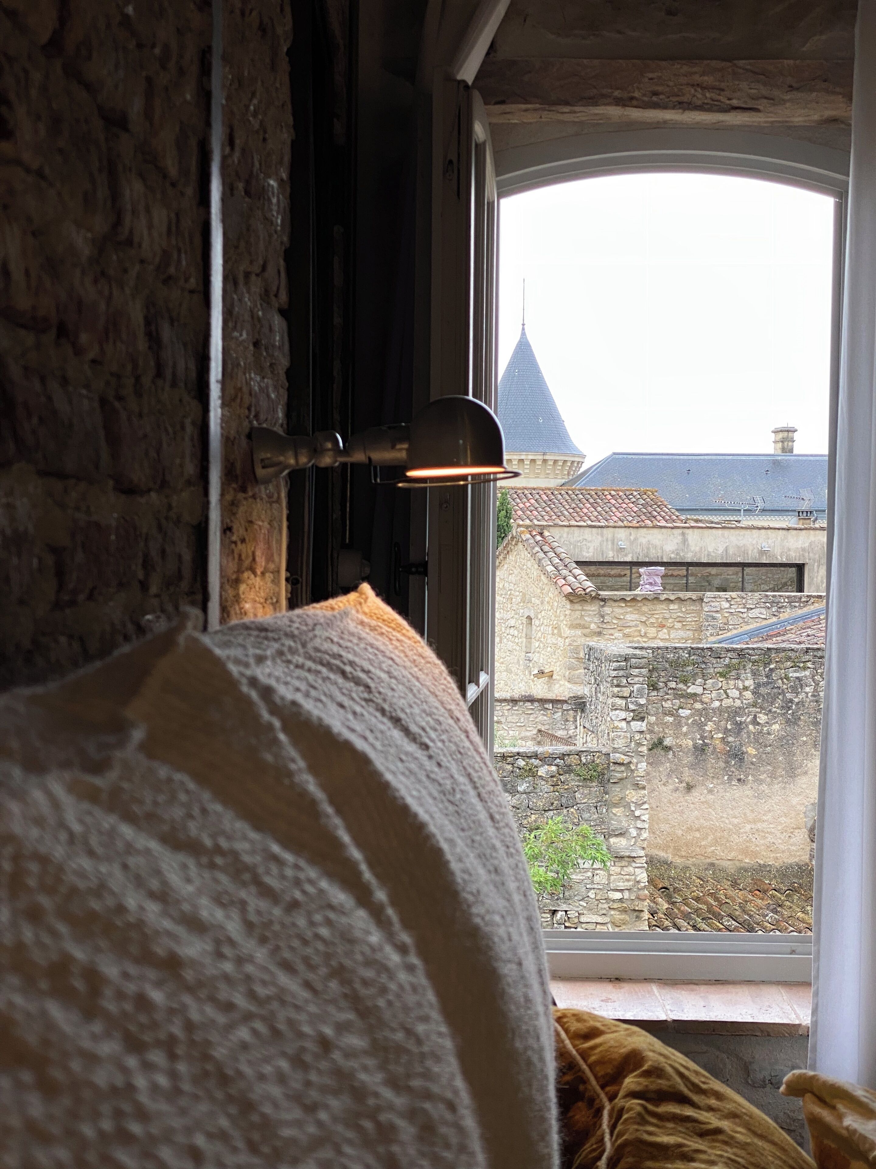 A room with a window overlooking a stone building and a tower.