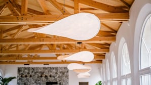 A room with wooden beams, large windows, and hanging pendant lights.