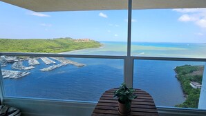 Een balkon met uitzicht op een jachthaven en een kustlandschap.