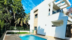 Ein moderner Poolbereich mit rechteckigem Pool, Holzterrasse und einem Gebäude mit Balkonen.