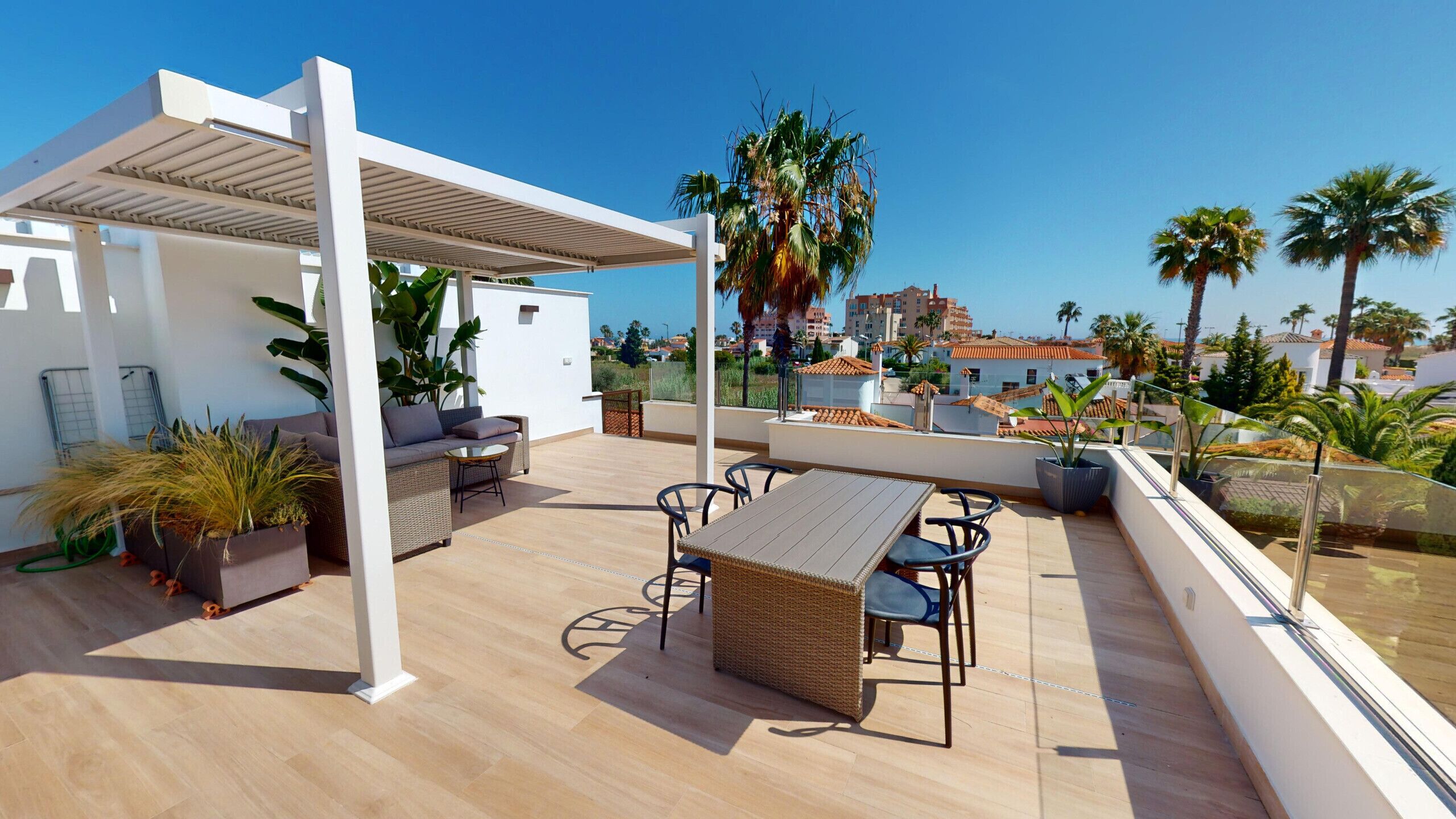 Eine Dachterrasse mit überdachter Sitzgelegenheit, einem Tisch und Stühlen.