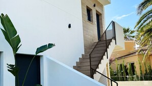 Ein modernes Gebäude mit weißer Fassade, einer Holztreppe und einem Blumentopf.