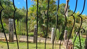 Una ventana con barrotes, vista a un área verde con árboles y un cielo azul despejado.