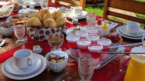 Una mesa al aire libre dispuesta para el desayuno, con diversos alimentos, vasos y una jarra de jugo.