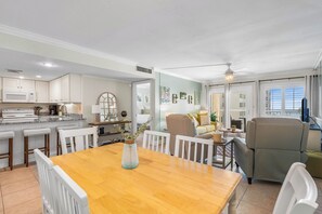 A modern kitchen with white cabinets, a wooden dining table, and a vase with a plant. - 410- Newly added 2 BR/ 2 BA Condominium with Free Beach Service! (Destin)
