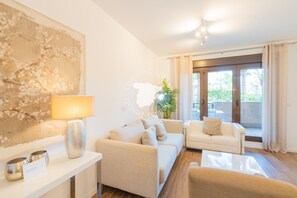 A modern living room with a sofa set, a lamp, a decorative wall piece, and a view through a glass door.