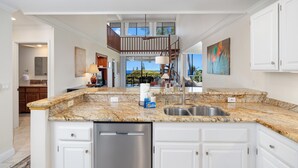 A modern kitchen with granite countertops, stainless steel appliances, and white cabinetry.