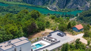 Un bâtiment moderne doté d’une piscine sur le toit, entouré d’une végétation luxuriante et offrant une vue sur une rivière.