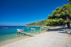 Ein Strand mit klarem türkisblauem Wasser, Booten und Menschen.