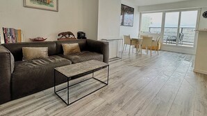 Un salon moderne avec un canapé gris, une table basse et un coin repas comprenant des chaises et une table.