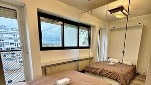 Une chambre d’hôtel avec deux lits, une grande fenêtre et un miroir.