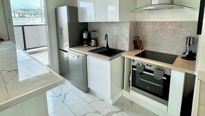 Une cuisine moderne avec des meubles blancs, un four encastré et un lave-vaisselle.