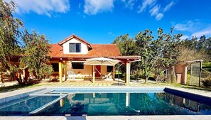Une maison avec une piscine, un patio couvert et une cour clôturée.