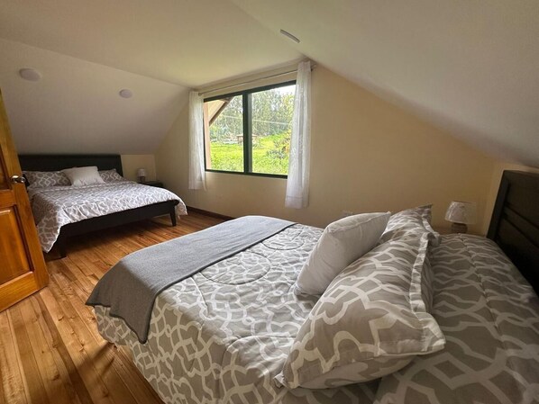 Une chambre avec deux lits, une fenêtre avec des rideaux et un plancher en bois.