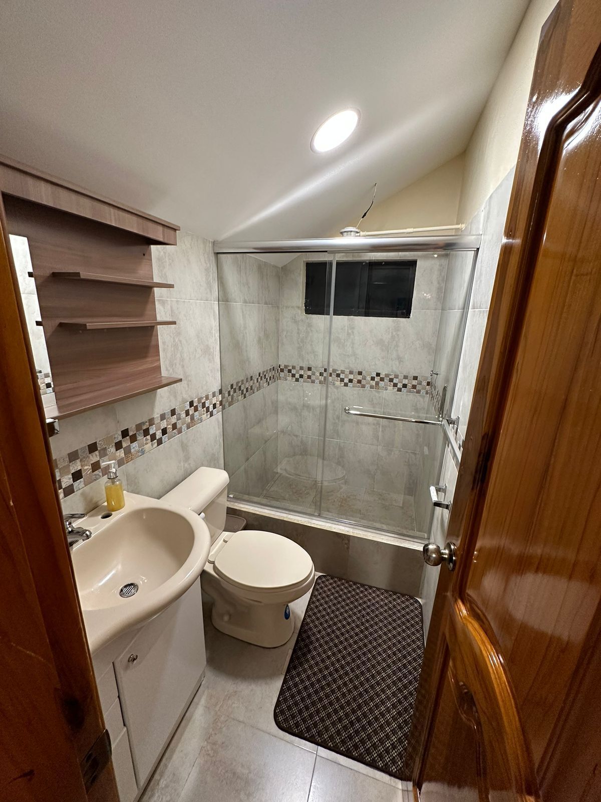 Une petite salle de bain comprenant un lavabo, des toilettes et une cabine de douche.