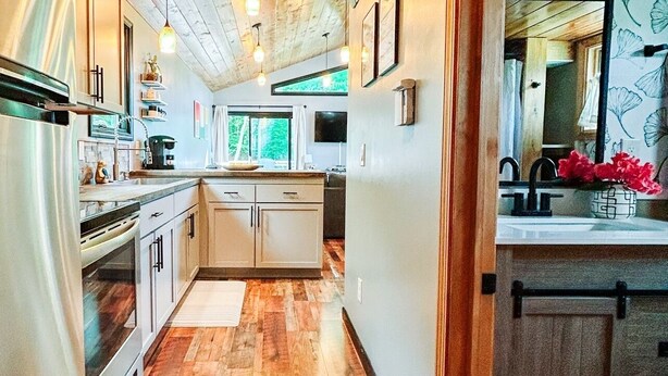 A modern kitchen with wooden ceiling beams, a central island, and a view of the outdoors.
