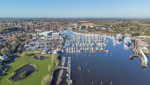 A marina with numerous boats docked, surrounded by residential buildings and greenery. - Newgate Cottage by NewFo rest (Lymington)