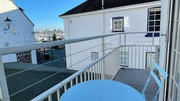 Enjoy the marina views from this building's balcony, featuring a table and metal railing.