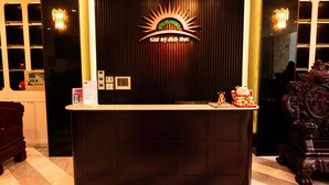 A reception desk with a logo, a chandelier, and a statue. - Solis Hotel (Hai Phong)