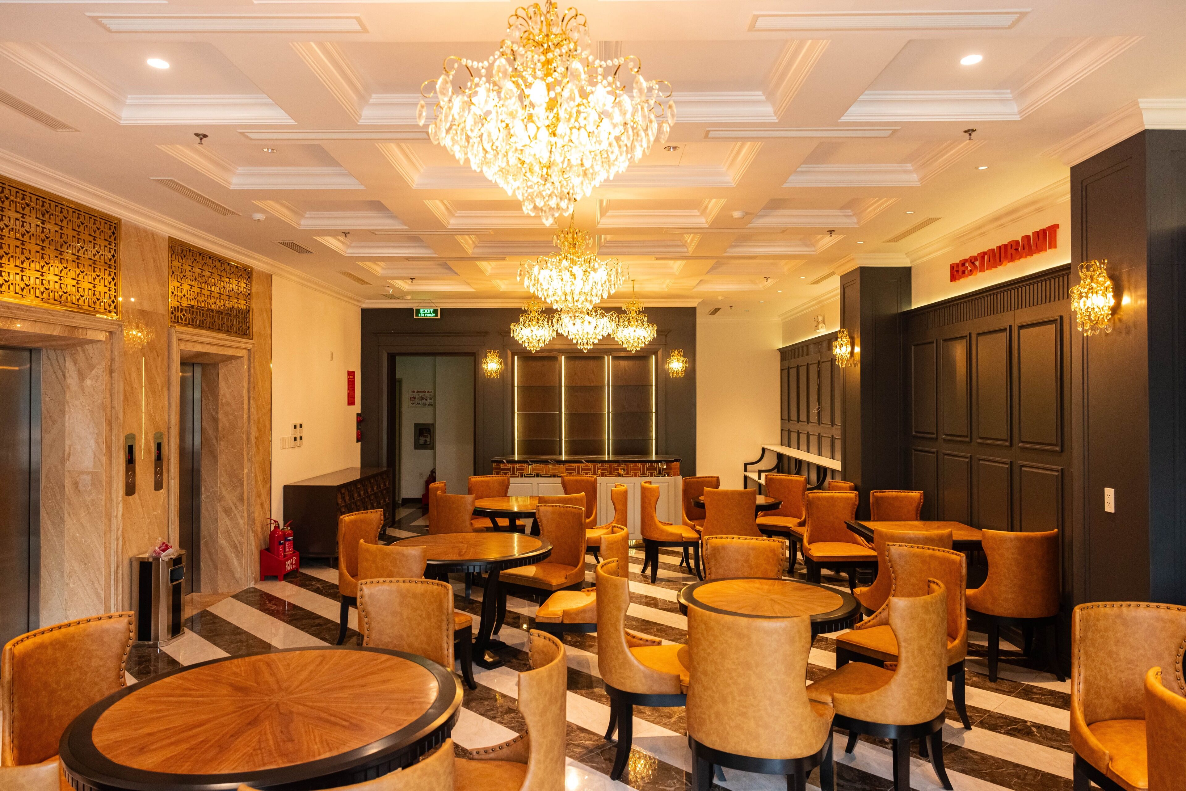 A hotel lobby with multiple seating areas, a chandelier, and a sign indicating a restaurant.
