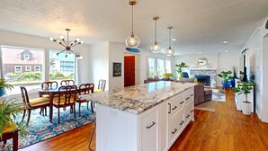 A spacious kitchen with a large island, wooden flooring, and pendant lighting.