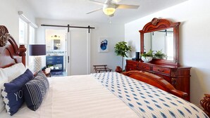 A bedroom with a bed, dresser, and a large mirror.