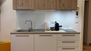 Una cocina moderna con un gabinete superior de madera, un lavamanos de acero inoxidable y una cafetera.
