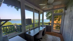A room with a desk, chair, and a view of a lake.
