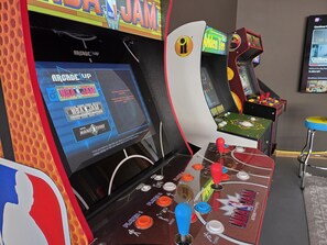A gaming arcade with multiple basketball-themed machines, including a prominent NBA JAM Tournament Edition machine.