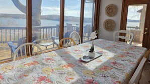 A dining area with a table set for two, overlooking a lake.