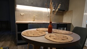 A modern kitchen with a round dining table, chairs, and a vase with dried plants. - Vivis Hub (Kefalonia)