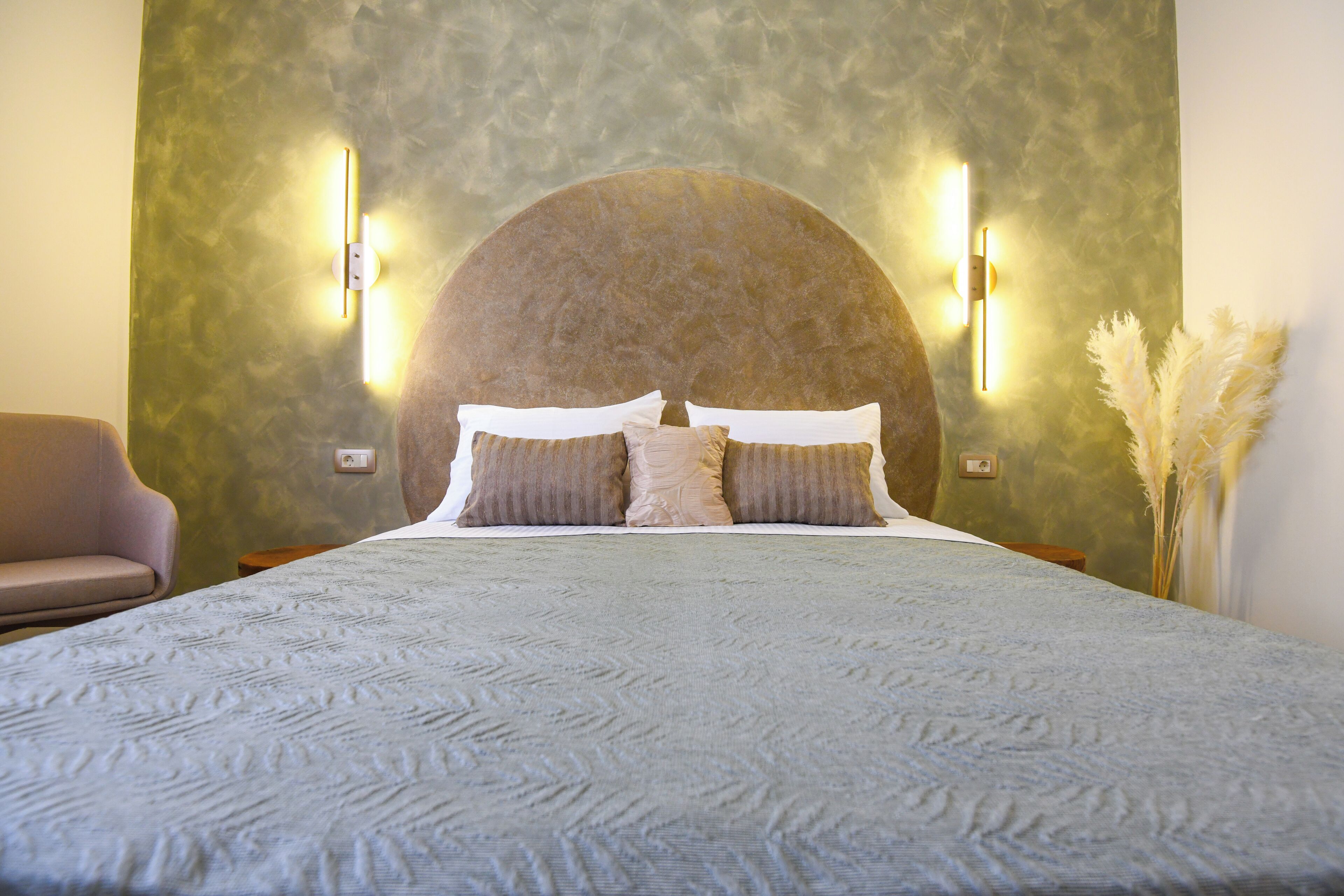 Een slaapkamer met een groot bed, twee wandlampen en een slaapbank.