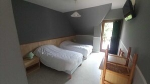 Ein Schlafzimmer mit zwei Betten, einem Holzstuhl, einem Fernseher und einem Fenster.