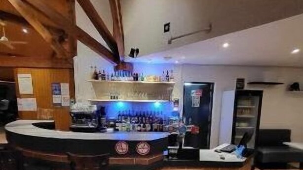 Eine Barbereich mit einer Theke, Hockstühlen und einem Kühlschrank.