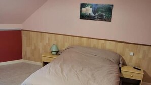 Ein Schlafzimmer mit Bett, Nachttischen, einer Lampe und einem Gemälde an der Wand.